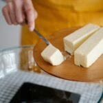 Focused shot of cutting butter for meal preparation, essential cooking ingredient.